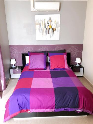 a bedroom with a purple and pink bed with two lamps at Le Rieussec in Saillans