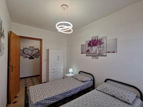 a bedroom with two beds and a chandelier at Villa Boito in Marina di Pescoluse