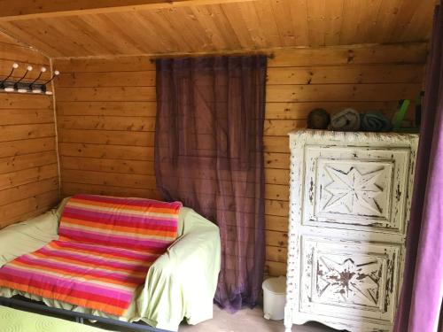 een bed in een houten hut met een kleurrijke deken bij la campagne de Mari in Peyrolles-en-Provence