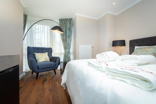 a bedroom with a bed and a blue chair at Hotel Allegra in Heinsberg
