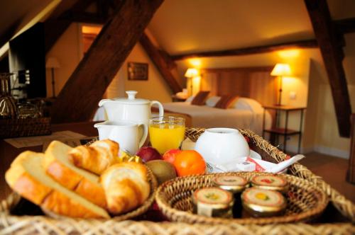 a breakfast table with a basket of bread and fruit at Hôtel Saint-Laurent, The Originals Relais in Montfort-lʼAmaury