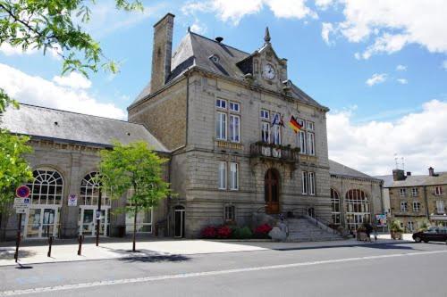 un grand bâtiment en pierre avec une horloge en haut dans l'établissement Appartement familial le Tanis, à Pontorson