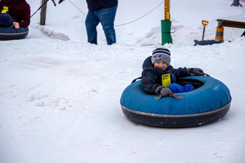 a young child is riding in a tube in the snow at Villa Roma Resort and Conference Center in Callicoon