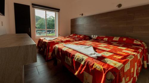 a bedroom with two beds and a window at Hotel Galería del Ángel in Santa Cruz Huatulco