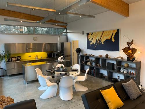 a kitchen and living room with a table and chairs at La Maison d'Architecte en pleine nature - le "Clos des Chevreuils" in Barbençon