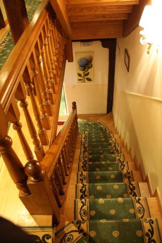 a stairway with a green carpet and wooden stairs at Hostería La Antigua in Potes