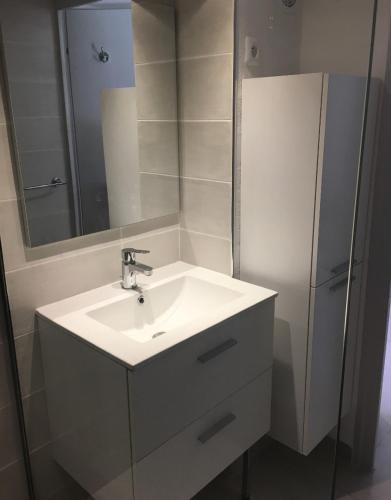 une salle de bain avec un lavabo blanc et un miroir dans l'établissement Aqua Plage, au Cap d'Agde