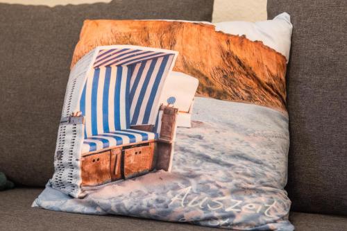 a pillow with a beach chair on a couch at Ferienwohnung Smillenzweg mit Garten in Lohme