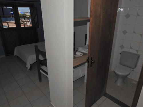 uma casa de banho com um WC, uma mesa e uma cama em Pousada Sombra das Ondas em Guarapari