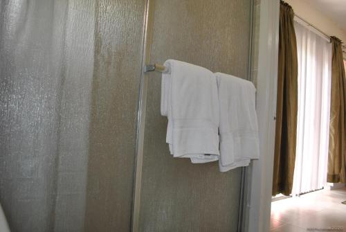 a bathroom with white towels hanging on a shower door at Tropical Hideaway in Nassau
