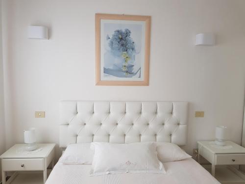 a bedroom with a white bed with two tables and a picture at Hotel Ristorante Radar in Carrara