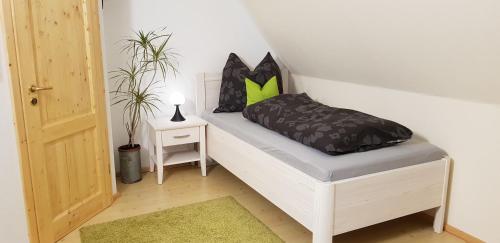 een wit bed met zwarte en groene kussens erop bij Ferienhaus Dorfschmiede in Schönau