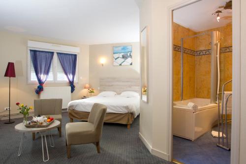 Hotel du Port et des Bains في سانت فاليري سور سوم: غرفة في الفندق مع سرير وحوض استحمام