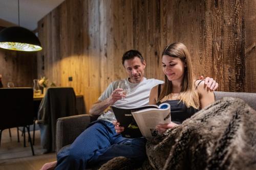 a man and a woman sitting on a couch with a glass of wine at K1 Mountain Chalet - Luxury Apartements in Brunico