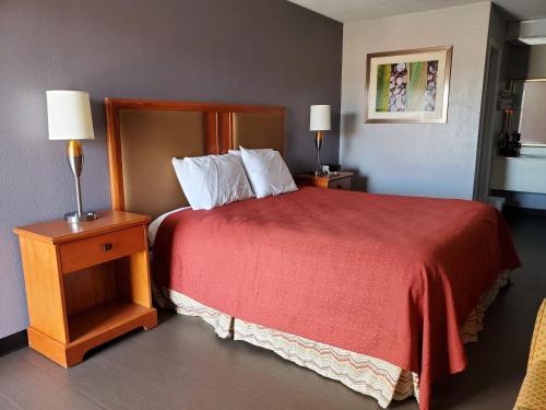 a hotel room with a bed with a red bedspread at Americas Best Value Inn Wildersville in Wildersville