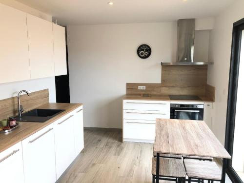 une cuisine avec des armoires blanches et une table en bois dans l'établissement Chez Fred et Marie, à Figari