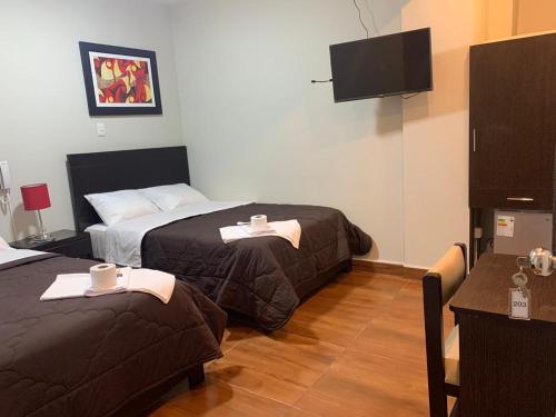 a hotel room with two beds and a flat screen tv at ORBEGOSO - Trujillo in Trujillo