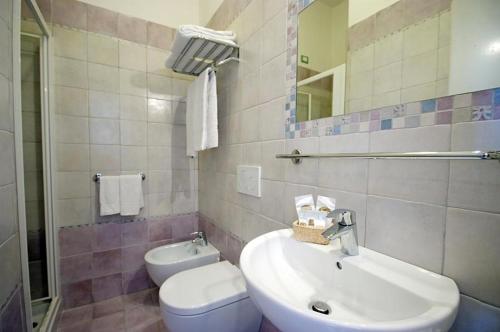 ein Badezimmer mit einem Waschbecken, einem WC und einem Spiegel in der Unterkunft Hotel Alma in Campo nell'Elba