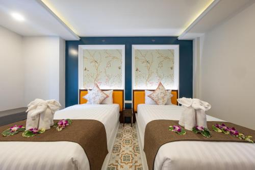 twee bedden in een kamer met twee ramen bij Sino Siam Hotel in Klong Muang Beach
