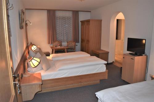 a hotel room with two beds and a television at Hotel Pension Lindenhof in Prien am Chiemsee