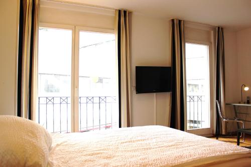a bedroom with a bed and two large windows at a-partment Cologne Riverside in Cologne