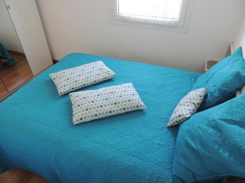 una cama azul con almohadas encima en Cathymini à Sete, en Sète