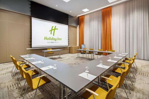 a conference room with a long table and yellow chairs at Holiday Inn - Hamburg - HafenCity by IHG in Hamburg