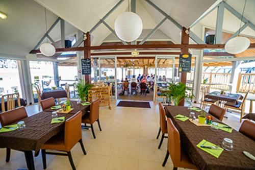 un restaurant avec des tables et des chaises et des personnes en arrière-plan dans l'établissement Mobile Home For You Quiberon, à Quiberon