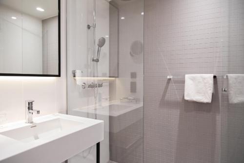 赫爾辛基的住宿－Holiday Inn Helsinki - Expo, an IHG Hotel，白色的浴室设有水槽和淋浴。