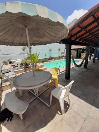 een tafel en stoelen onder een parasol naast een zwembad bij Rock n Hostel in Cabo Frio