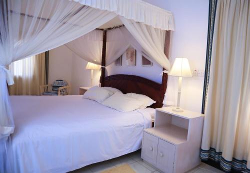 ein Schlafzimmer mit einem weißen Bett mit Baldachin in der Unterkunft Woburn Residence Club Apartments in Malindi