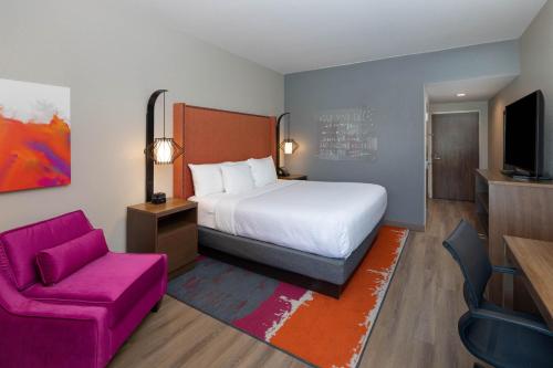 a hotel room with a bed and a purple chair at La Quinta by Wyndham Perry in Perry