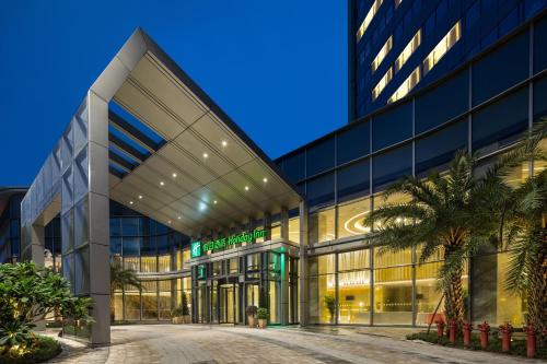 an external view of a building with palm trees in front at Holiday Inn Shaoguan Downtown by IHG in Shaoguan