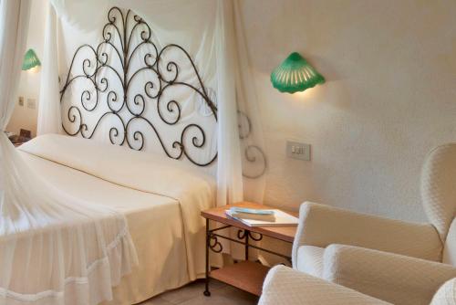 a bedroom with a bed and a chair and a table at Hotel Capo d'Orso Thalasso & SPA in Palau