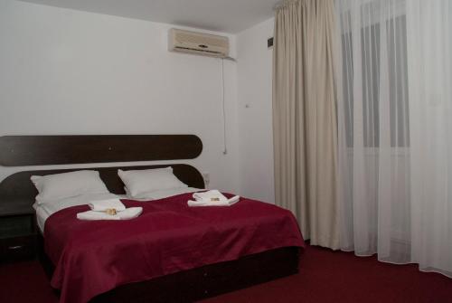 a bedroom with a bed with two towels on it at Pensiunea Otopeni in Otopeni