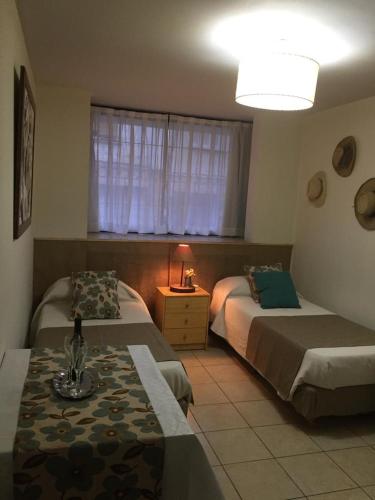 1 dormitorio con 2 camas, mesa y ventana en Acogedor monoambiente , en el centro de mendoza . en Mendoza
