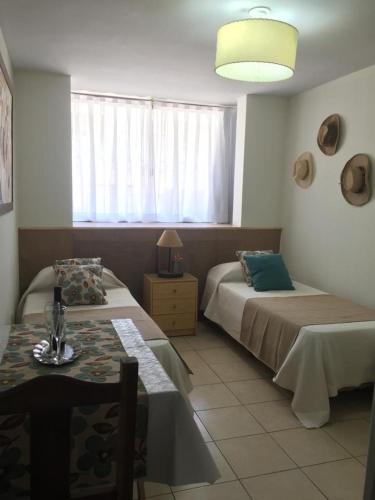 1 dormitorio con 2 camas, mesa y ventana en Acogedor monoambiente , en el centro de mendoza . en Mendoza
