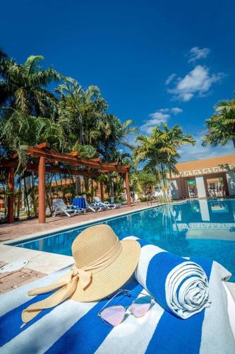 a straw hat and a sunvisor sitting next to a swimming pool at Tecnohotel Itzáes in Mérida