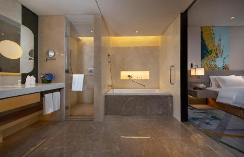 Holiday Inn Hangzhou Airport Zone, an IHG Hotel في Xiaoshan: حمام مع حوض استحمام ودش وسرير