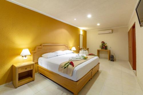1 dormitorio con 1 cama grande y pared amarilla en Tecnohotel Itzáes en Mérida