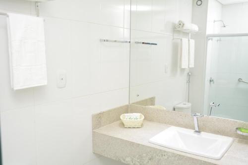 a white bathroom with a sink and a mirror at Real Classic Bahia Hotel in Salvador