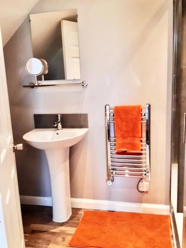 a bathroom with a sink and a mirror and orange towel at Stanton House Annex in Bakewell
