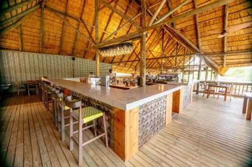 a kitchen with a bar with chairs and tables at Shearwater's Explorers Village in Victoria Falls