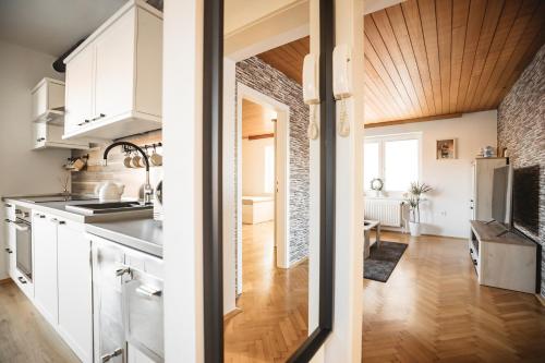 a kitchen with white cabinets and a wooden ceiling at Drive Caffe Apartments in Trzin