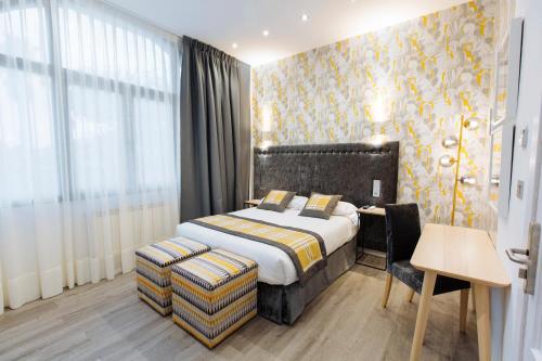 a bedroom with a bed and a desk with a chair at Hotel Santa Cruz in Cangas de Onís