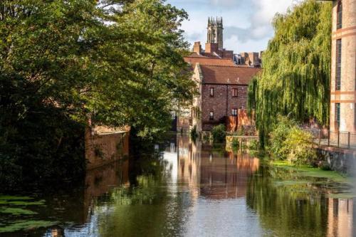 a river in a city with a building and trees at Cocoa Lily - River fronted studio with secure parking in York
