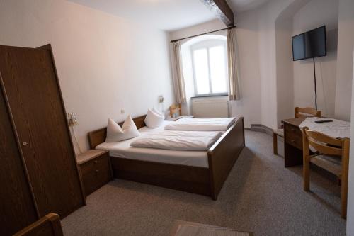 1 dormitorio con cama, mesa y ventana en Bistro-Pension Vis-a-Vis, en Vohburg an der Donau