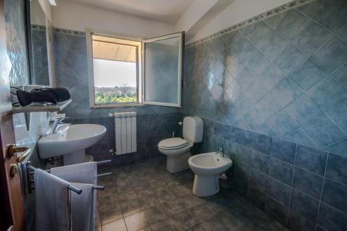 a bathroom with a sink and a toilet and a window at New Naxos Village in Giardini Naxos