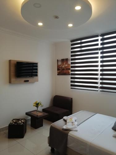 a bedroom with a bed and a chair and a window at Hostal Perla Real Inn in Guayaquil