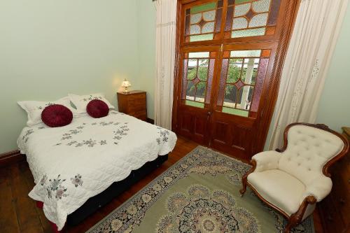 een slaapkamer met een bed, een stoel en een raam bij Harold House in Reefton